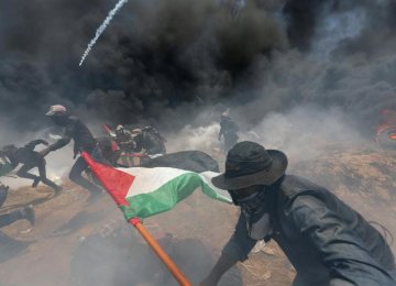 Palestinian demonstrators run for cover from Israeli fire and tear gas on May 14.
