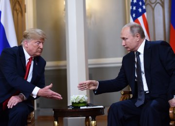 Russian President Vladimir Putin (R) and US President Donald Trump reach to shake hands before a meeting in Helsinki, on July 16.