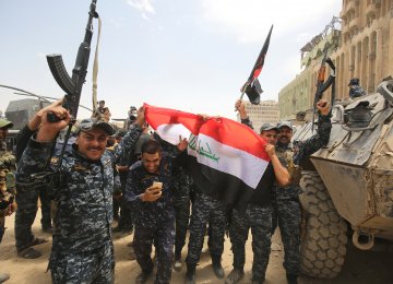 Members of the Iraqi federal police wave their country’s national flag in celebration in the Old City of Mosul.