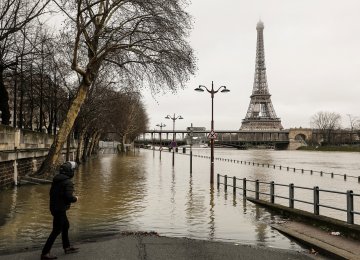 A man stands by the flooded banks of the river Seine in Paris on January 23, near the Eiffel tower as the Seine level has risen to a height of 4.57 metres, several metres higher than its normal level.