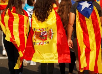 Youths wrapped in a Catalan, a Spanish and an Estelada (Catalan separatist) flag walk through a street during a protest two days after the independence referendum in Barcelona on October 3.