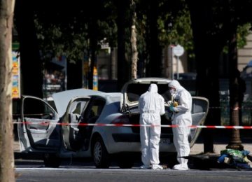 Police officers inspect a burned car on the Champs-Elysees Avenue in Paris, France, on June 19.