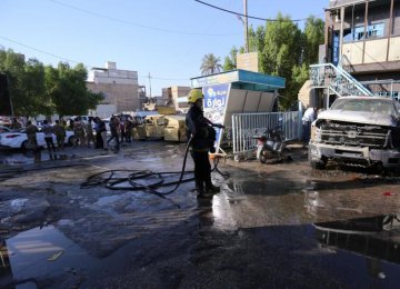 A firefighter hoses down a street after a suicide attack in Karbala