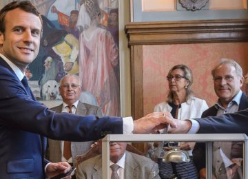 French President Emmanuel Macron (L) casts his ballot in the first round of the two-stage legislative elections, in Le Touquet, northern France, on June 11.