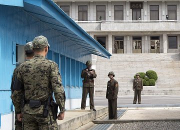 A North Korean soldier takes photographs of South Korean soldiers at the truce village of Panmunjom. (File Photo) 