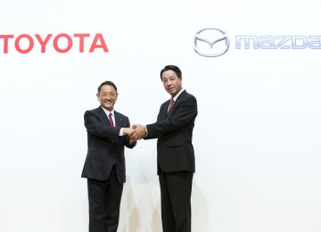 Toyota CEO Akio Toyoda (L) shakes hands with Mazda CEO Masamichi Kogai.