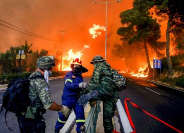 Firemen and soldiers escape from spreading flames near Athens.