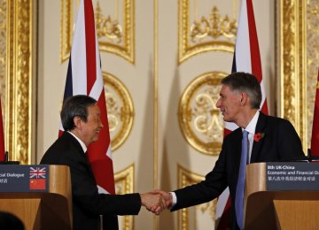 Ma Kai (L) and Philip Hammond shake hands after the press conference in Beijing, Dec. 16.
