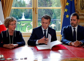 President Emmanuel Macron (C) signs a set of executive orders making sweeping changes to France’s complex labor laws on Friday.