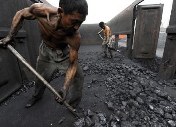 Workers unload coal at a storage site along  a railway station in Hefei, China.