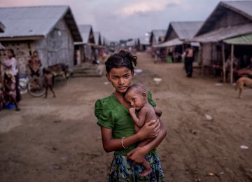 Oma Salema, 12, holds her undernourished brother Ayub Khan, 1, at a camp for Rohingya in Sittwe, Myanmar.