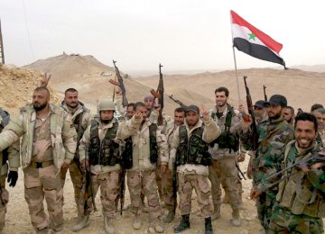 Syrian soldiers flash the victory sign.