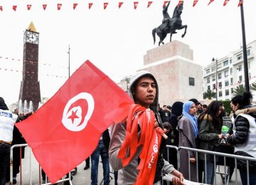 A Tunisian peddler selling national flag crosses a police roadblock on his way to a rally in the capital Tunis on Jan. 14.
