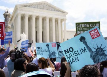 Protesters hold up signs and call out against the Supreme Court ruling upholding Trump’s travel ban outside  the Supreme Court in Washington on June 26.