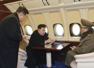 North Korean leader Kim Jong-un (C) talks with officials onboard his personal plane in this undated photo released by North Korea’s KCNA.