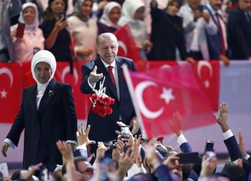 Turkey’s President Recep Tayyip Erdogan (R) accompanied by his wife Emine throws flowers to his supporters as he arrives to deliver a speech at his ruling Justice and Development Party congress in Ankara, Turkey, on August 18.