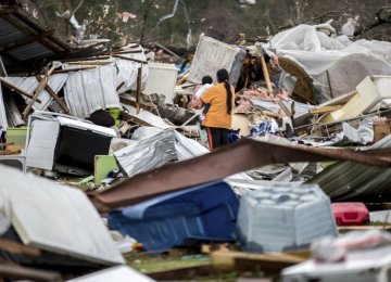 A woman holds a child while walking through a farm that was damaged  by a tornado on Jan. 22.