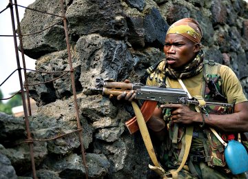 A Congolese soldier positions himself behind a wall during a firefight.