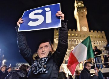 A woman wears a mask of Italian Premier Matteo Renzi as she holds up a sign reading “Yes” during a rally in Florence, Italy, on Dec. 2.