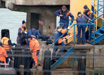 Russian rescuers carry a stretcher with a body recovered after the Russian military plane crashed in the Black Sea, on a pier outside Sochi, on December 25, 2016.