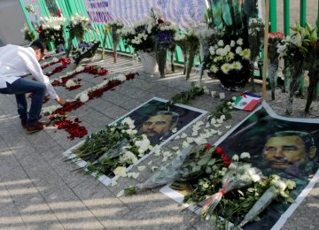 A supporter places flowers beside pictures of Fidel Castro as he attends a tribute ceremony, following the announcement of the death of Cuban revolutionary leader Castro outside the Cuban Embassy, in Mexico City, Mexico, on Nov. 27.