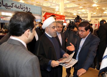 Ali Reza Bakhtiari, publisher and managing director of Financial Tribune and Donya-e-Eqtesad briefs President Hassan Rouhani at the fair in Tehran on Nov. 15. 