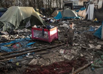 A five-year-old Kurdish boy from Iraq stands amid rubbish in the Calais camp.