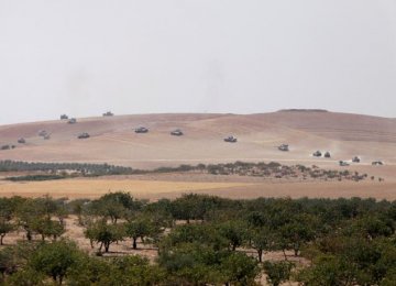 Turkish army tanks and Turkish-backed Syrian fighters make their way in the Syrian border town of Jarablus as it is pictured from the Turkish town of Karkamis, in the southeastern Gaziantep province, Turkey, August 24 .