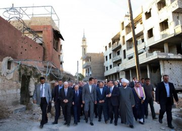 Syrian President Bashar Assad (C) walks with officials after performing the Eid al-Adha prayers in Daraya, a blockaded Damascus suburb in Syria on Sept. 12.