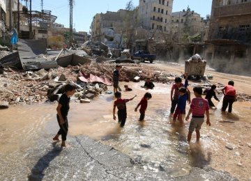 Children play with water from a burst pipe at a site hit by an airstrike in Aleppo’s militant-controlled al-Mashad neighborhood, Syria, on Sept. 30.  