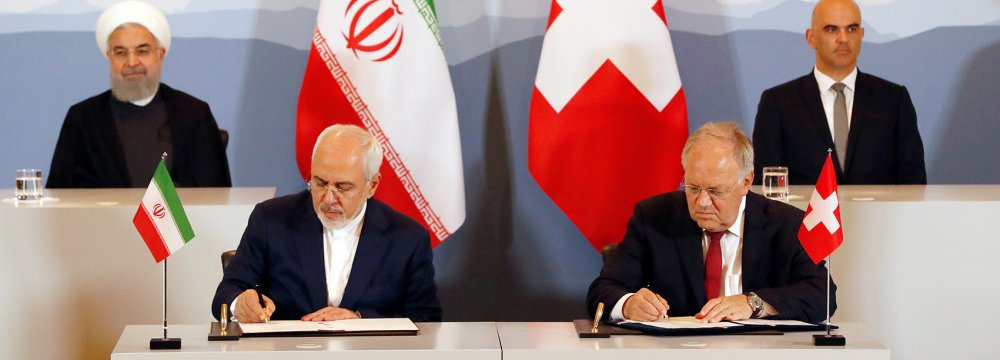 President Hassan Rouhani (top- L) and President Alain Berset (top-R) watch as Foreign Minister Mohammad Javad Zarif (L) and Swiss Economic Minister Johann Schneider-Ammann sign an agreement in Bern on July 3.