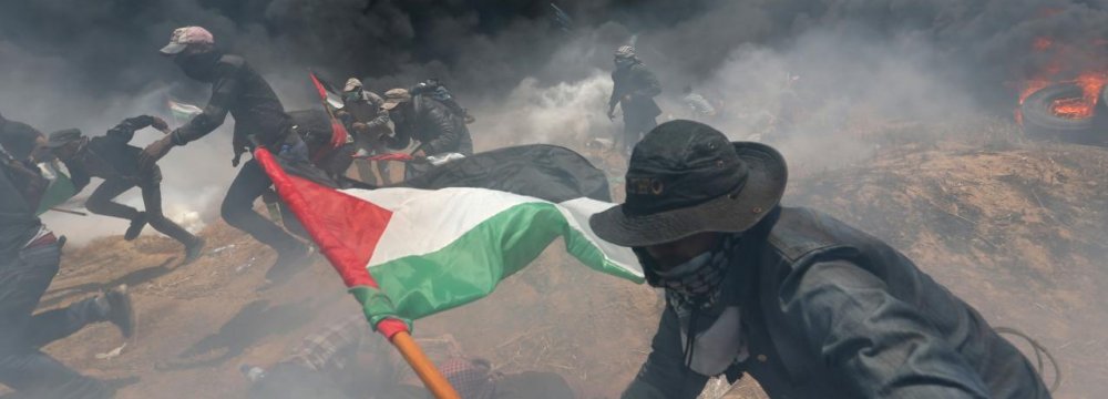Palestinian demonstrators run for cover from Israeli fire and tear gas on May 14.
