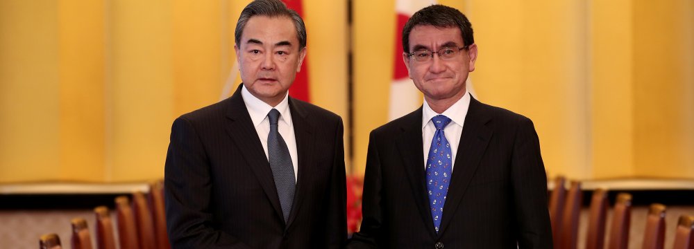 Chinese Foreign Minister Wang Yi (L) shakes hands  with Japan’s Foreign Minister  Taro Kono in Tokyo, April 15.