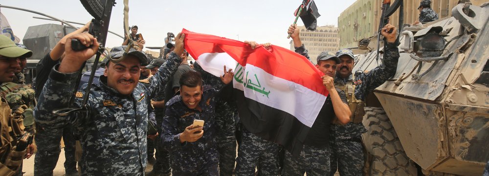 Members of the Iraqi federal police wave their country’s national flag in celebration in the Old City of Mosul.