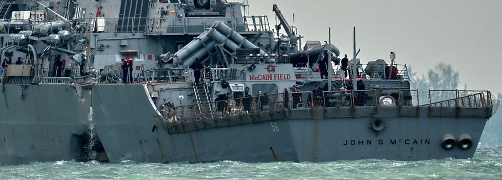The destroyer USS John S. McCain, with a hole on its portside after a collision with an oil tanker, makes its way to Changi naval base in Singapore on August 21.