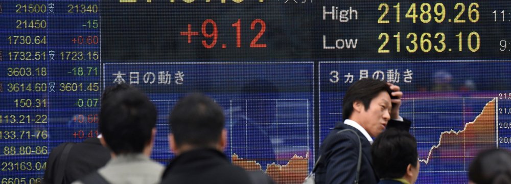 Pedestrians are reflected on a window displaying share prices of the Tokyo Stock Exchange in Tokyo on October 23, 2017. 