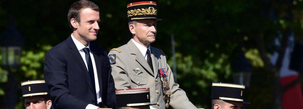 French President Emmanuel Macron (L) and former armed forces chief General Pierre de Villiers ride aboard a command car during the Bastille Day military parade in Paris on July 14.