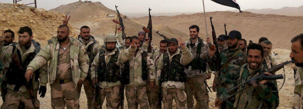 Forces loyal to Syria’s President Bashar al-Assad flash victory signs and carry a Syrian national flag on the edge  of the historic city of Palmyra (File Photo)