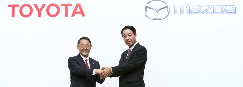 Toyota CEO Akio Toyoda (L) shakes hands with Mazda CEO Masamichi Kogai.