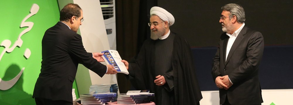 President Hassan Rouhani receives the atlas from Health Minister Hassan Hashemi (L) as Interior Minister Abdolreza Rahmani-Fazli (R) looks on.