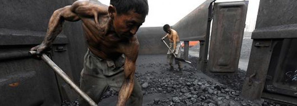 Workers unload coal at a storage site along  a railway station in Hefei, China.