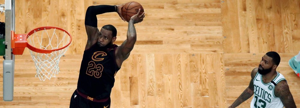 Cleveland Cavaliers forward LeBron James soars to dunk in front of Boston Celtics players.