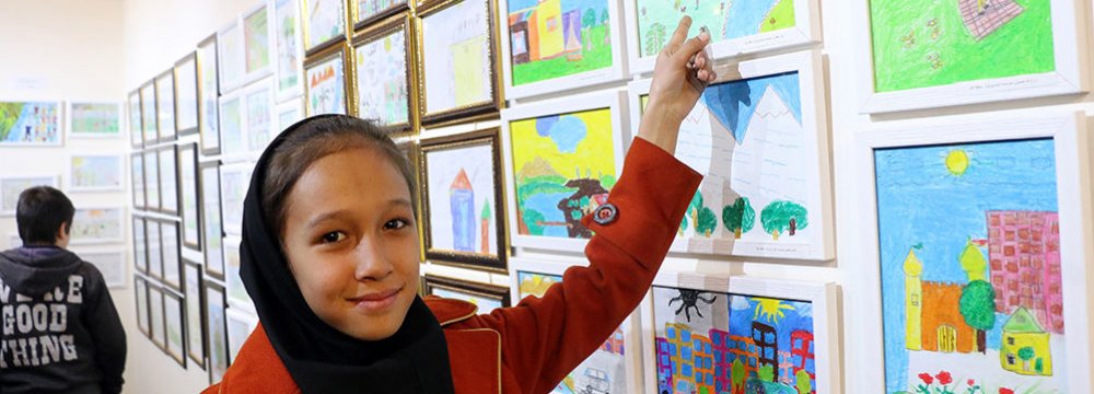 A young girl shows her painting at the exhibit.  