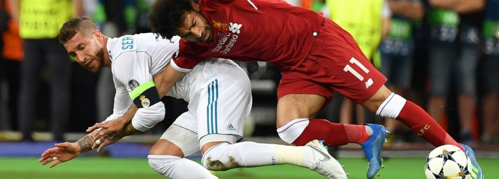  Mohamed Salah (R) goes down after a challenge from Real Madrid’s Sergio Ramos.