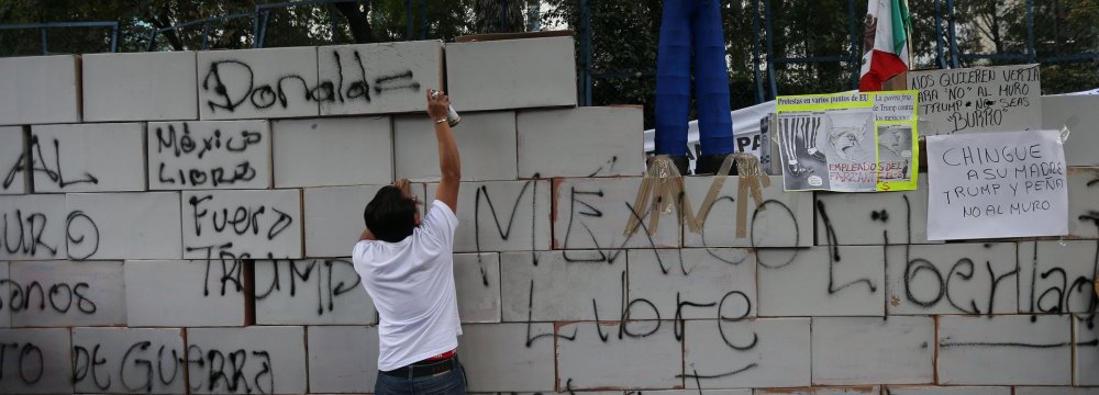 An effigy of Donald Trump stands on a symbolic wall built by protesters outside the US embassy in Mexico City.