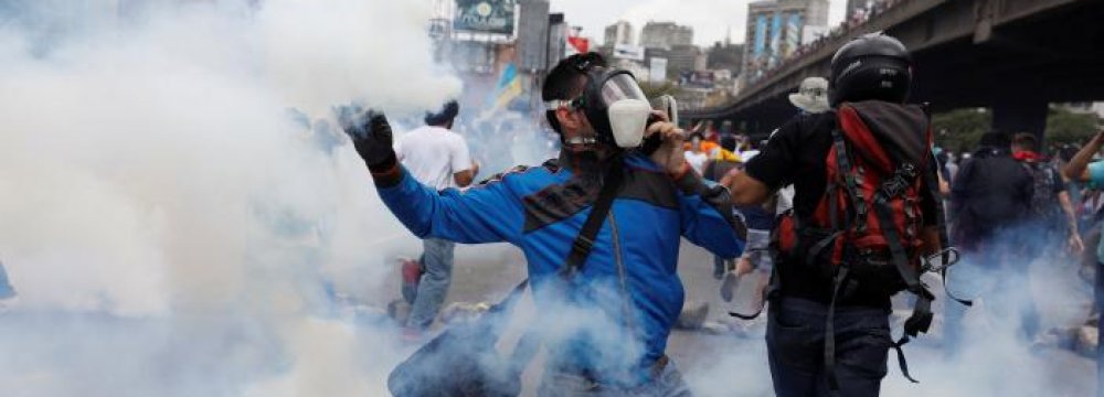 A demonstrator throws a tear gas canister back to policemen in Caracas, Venezuela, on April 6.