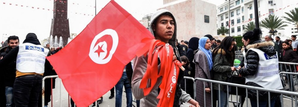 A Tunisian peddler selling national flag crosses a police roadblock on his way to a rally in the capital Tunis on Jan. 14.