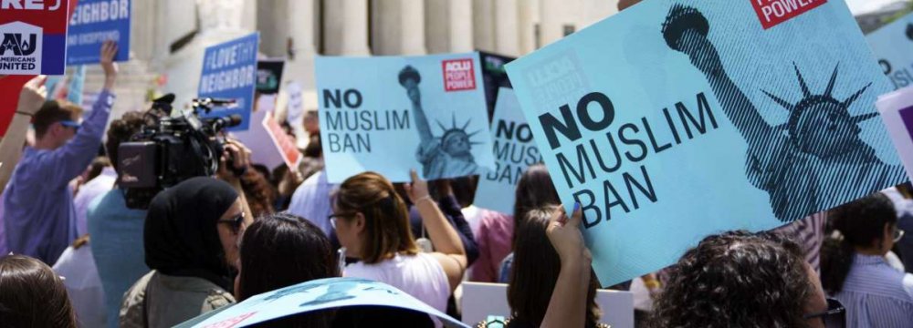Protesters hold up signs and call out against the Supreme Court ruling upholding Trump’s travel ban outside  the Supreme Court in Washington on June 26.