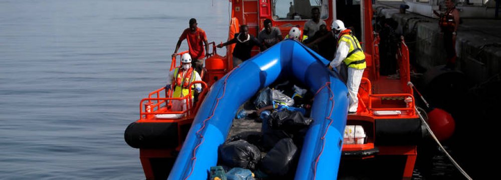 Migrants intercepted aboard a dinghy off the coast  in the Mediterranean Sea help rescuers unload their dinghy from a rescue boat after arriving at the port  of Malaga, southern Spain, on July 7.