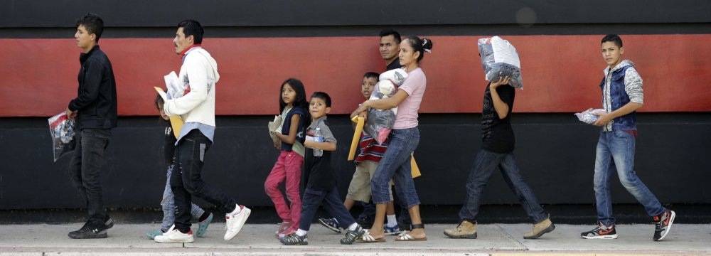 Immigrant families walk along a sidewalk on their way to a respite center after they were processed and released by US Customs and Border Protection on June 24 in McAllen, Texas.